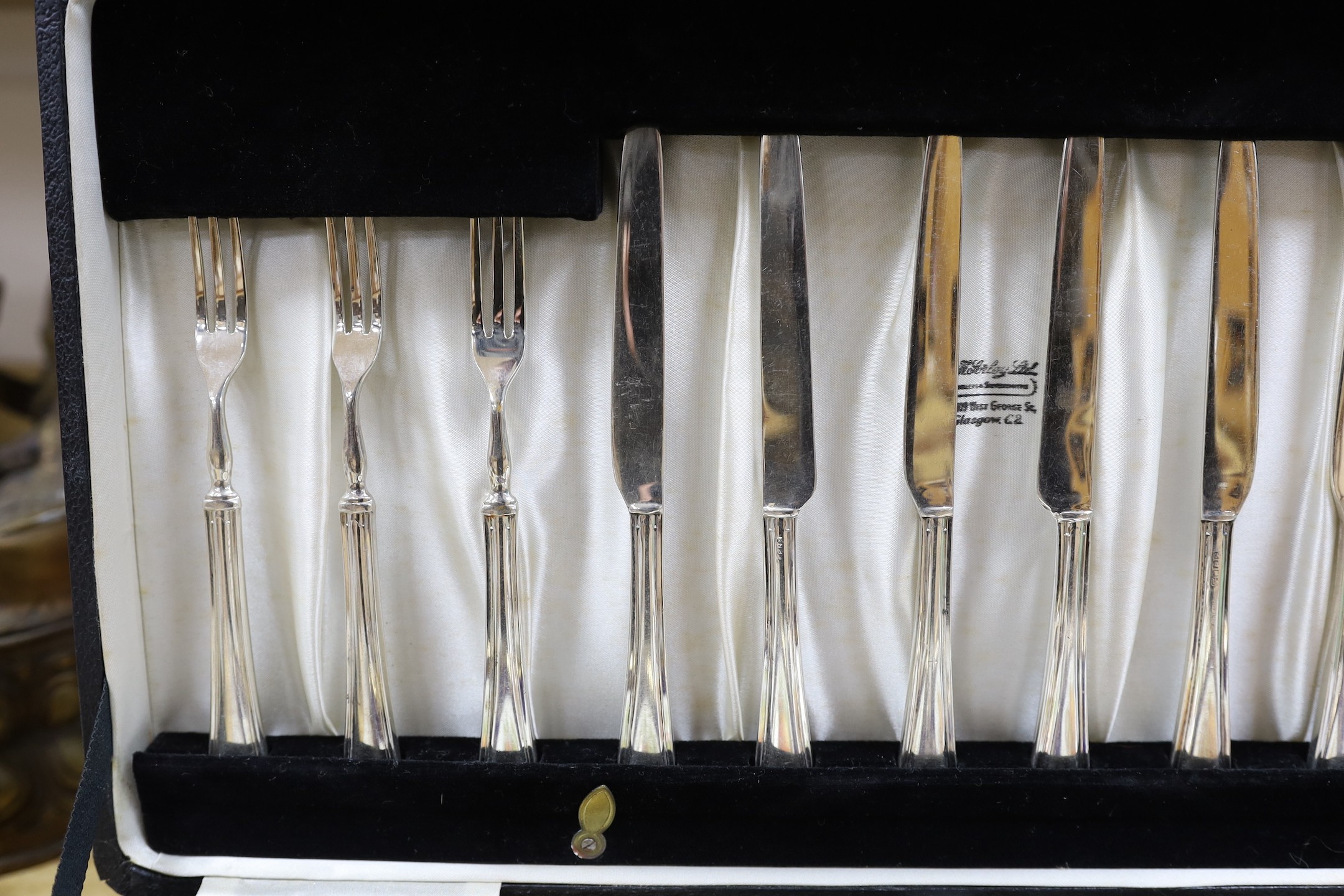 A cased dessert service containing six gilt and fruit decorated plates and a set of knives and forks